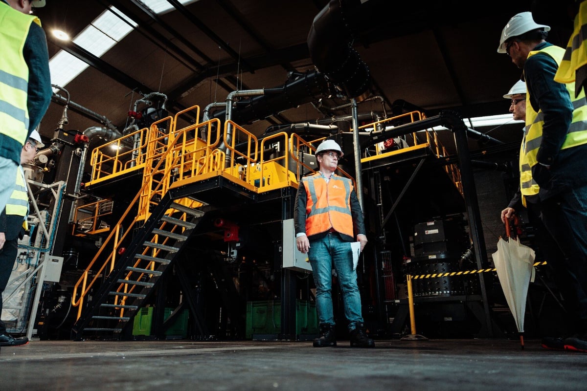 SK tes employee stands in front of battery recycling machinery