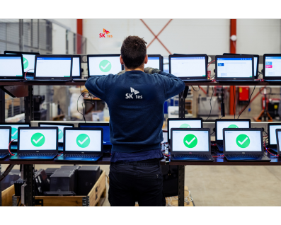 SK tes employee stands in front of row of laptops being securely data erased